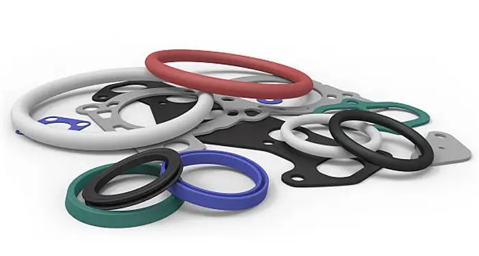 An assortment of multi-colored silicone gaskets and seals in red, blue, green, black, and white, featuring various sizes and shapes including circular, oval, and with bolt holes, all scattered on a plain white background.