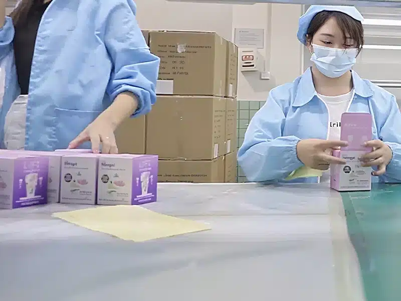 factory workers manually packing silicone products into retail packaging boxes
